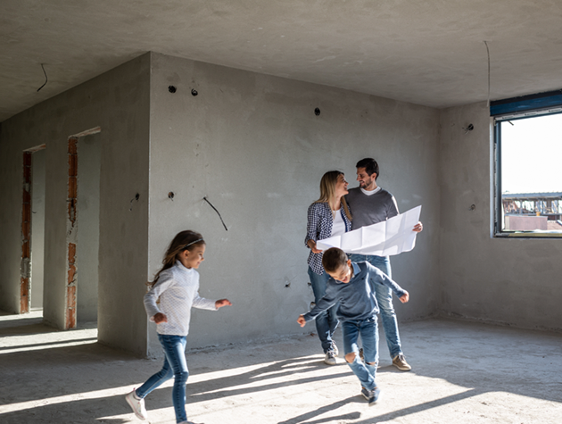 Man and woman looking at building plans with two children happily running around.
